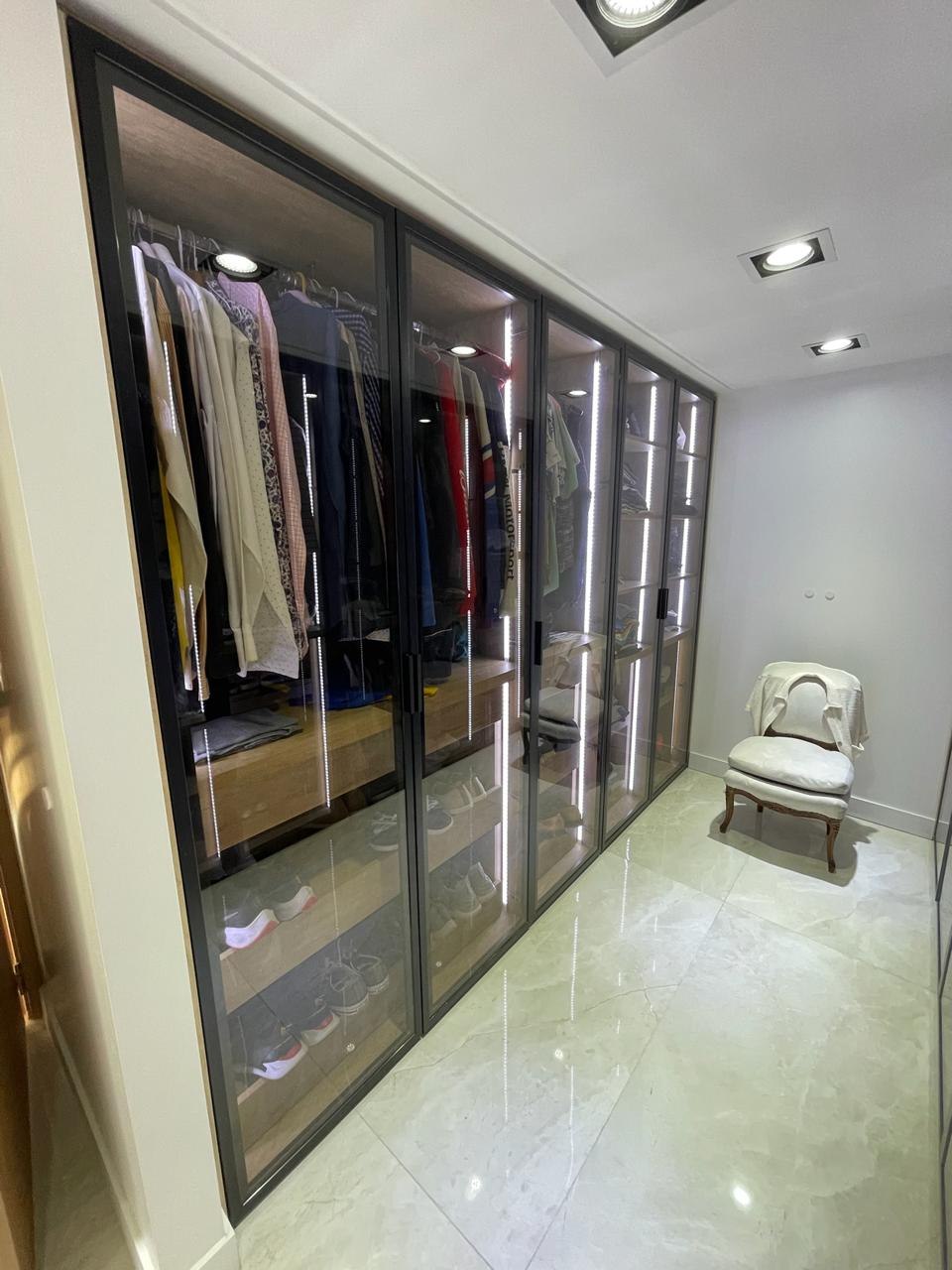 Vestidor a medida con puertas vidriadas de perfilería negra e iluminación LED interior
