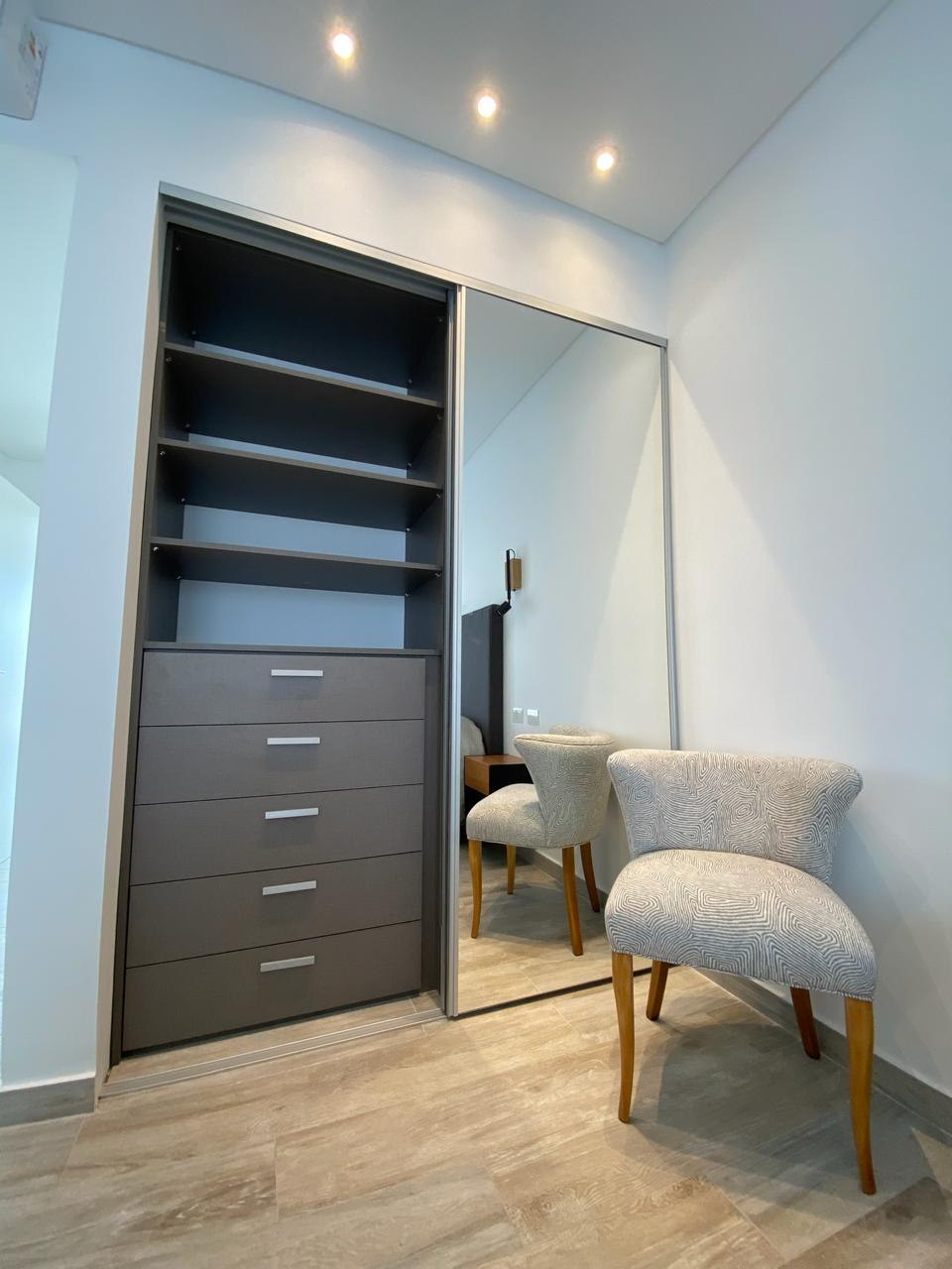 Placard a medida con puerta corrediza espejada, interior gris oscuro con estantes y cajonera de cinco cajones