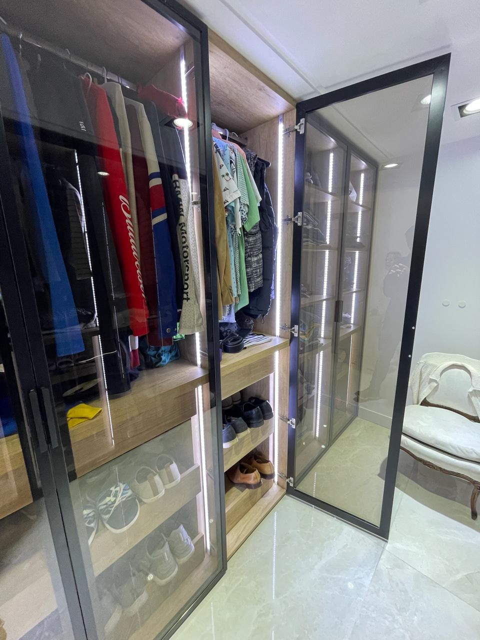 Vestidor a medida con módulos vidriados de piso a techo, barrales de colgado y zapatero iluminado